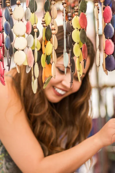 Primer plano de una hermosa mujer joven sonriente borrosa detrás de una artesanía en una tienda de mercado, telas de fondo — Foto de Stock