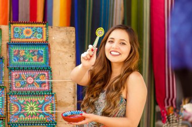 Onu tutan güzel gülümseyen genç kadın bir andean geleneksel kase bir kaşıkla, renkli kumaşlar arka plan eller