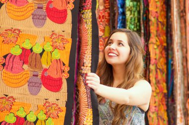 Güzel bir gülümseyen genç kadının and Giyim Tekstil iplik ve dokuma el ile geleneksel dokunmadan yakın yün, renkli kumaşlar arka planda