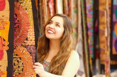 Genç bir kadının dokunaklı bir andean sırt çantası el ile tekstil iplik ve dokuma giyim geleneksel yakın yün, renkli kumaşlar arka planda