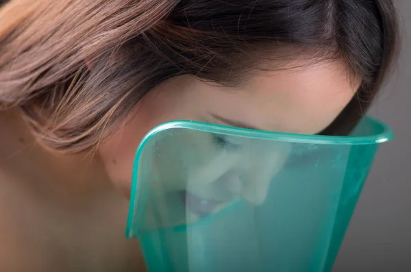 Close up of a beautiful woman doing inhalation with a vaporizer nebulizer machine on black background — Stock Photo, Image