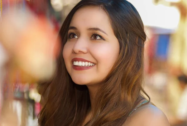 Primer plano de una hermosa joven sonriente que busca un arte tradicional andino colorido, en telas coloridas del mercado fondo — Foto de Stock