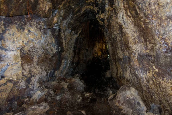 Hermosa cueva oscura en la isla de Rangitoto, hecha de formaciones volcánicas en Nueva Zelanda con algunas raíces en la parte superior de la cueva —  Fotos de Stock