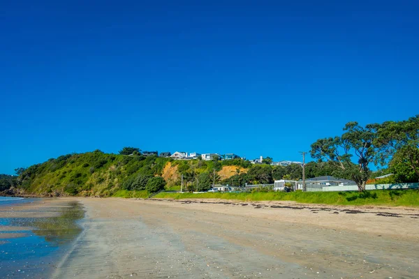 White Sand Beach en Waiheke Island, Nueva Zelanda con un hermoso cielo azul en un día soleado con algunas casas detrás — Foto de Stock