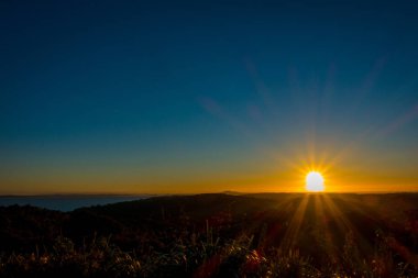 Güzel gün batımı Hauraki Körfez, ağaçlar ve ön planda kontrast tepeler üzerinde. Whakanewha kamp zemin Waiheke Island, Yeni Zelanda üzerinde plaj üzerinde gerçekleştirilen