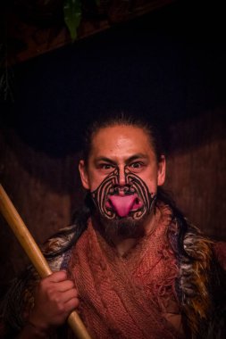 North Island, Yeni Zelanda - 17 Mayıs 2017: dil geleneksel kıyafet, Maori kültür, Tamaki kültür Köyü, Rotorua, Yeni Zelanda ve geleneksel olarak dövmesi yüz ile dışarı yapışmasını Maori adam