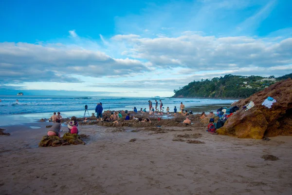 NORTH ISLAND, NEW ZEALAND- MAY 16, 2017: Tourists digging their own hot springs in Hot Water Beach, Coromandel. 130,000 annual visitors make it one of most popular attractions in Waikato region, in — Stock Photo, Image