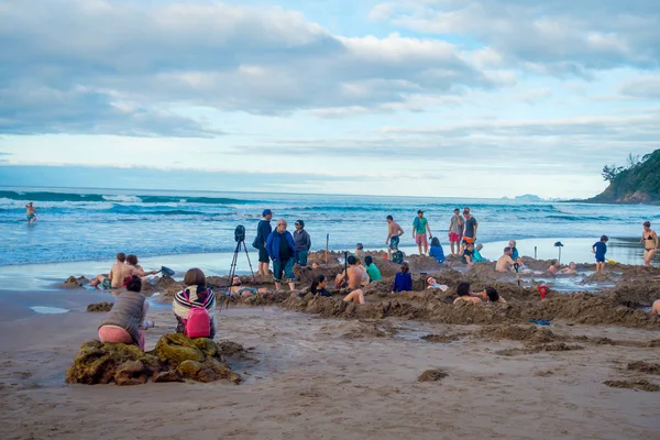 NORTH ISLAND, NEW ZEALAND- MAY 16, 2017: Tourists digging their own hot springs in Hot Water Beach, Coromandel. 130,000 annual visitors make it one of most popular attractions in Waikato region, in — Stock Photo, Image