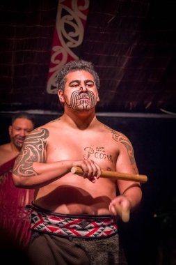 North Island, Yeni Zelanda - 17 Mayıs 2017: bir Tamaki Maori adamın Tamaki kültürel tahta bir sopa tutan Maori kültür Köyü'nde geleneksel kıyafet ve geleneksel olarak dövmesi yüz ile yakından