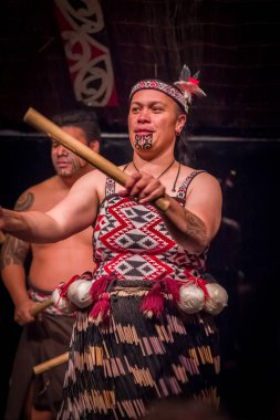 North Island, Yeni Zelanda - 17 Mayıs 2017: Tamaki Maori kadının geleneksel dövmesi yüz ve Tamaki tahta bir sopa tutan Maori kültür Köyü'nde geleneksel elbise ile yakından