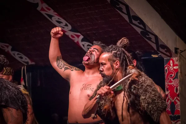 НОРТ-ОСТРОВ, НЬЮ-ЙОРК, 17 января 2017 года: Мужчины маори тамаки торчат из языка с традиционно татуированным лицом и в традиционной одежде в Культурной деревне маори, Роторуа, Новая Зеландия — стоковое фото
