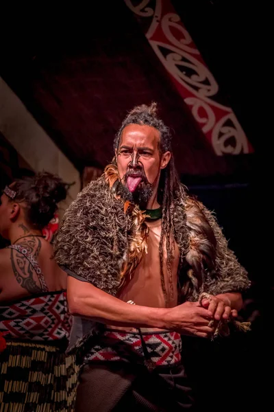 НОРТ-ОСТРОВ, НЬЮ-ЙОРК, 17 января 2017 года: мужчина маори тамаки, торчащий из языка с традиционно татуированным лицом и в традиционной одежде в Культурной деревне маори, Роторуа, Новая Зеландия — стоковое фото