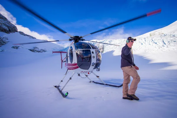 ILHA DO SUL, NOVA ZELÂNDIA - 24 DE MAIO DE 2017: Fechar o helicóptero e o piloto esperando sobre a neve por caçadores nos Alpes do Sul do Oeste, Nova Zelândia — Fotografia de Stock