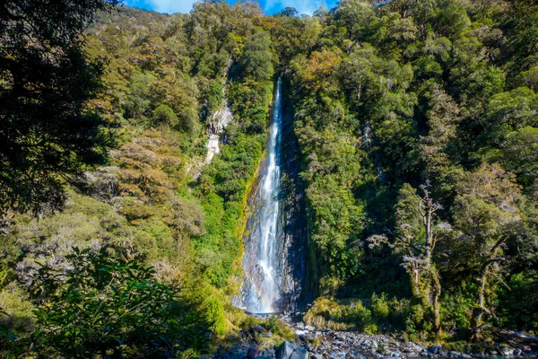 Billy Falls kayaların üzerinden akan buzul mavi nehir su ile. Haast Pass, South Island, Yeni Zelanda
