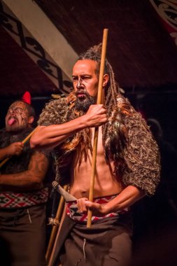 Maori kültür onun elinde tutan bir tahta sopa, Tamaki kültür Köyü, Rotorua adlı geleneksel elbise geleneksel olarak yüzüne dövmesi olan Takami Maori adam North Island, Yeni Zelanda - 17 Mayıs 2017: