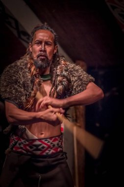 North Island, Yeni Zelanda - 17 Mayıs 2017: Maori onun elinde tahta bir sopa tutan ve yapıyor kültür geleneksel kıyafet giyen Takami Maori adamla dövmesi yüzünde, geleneksel olarak bir