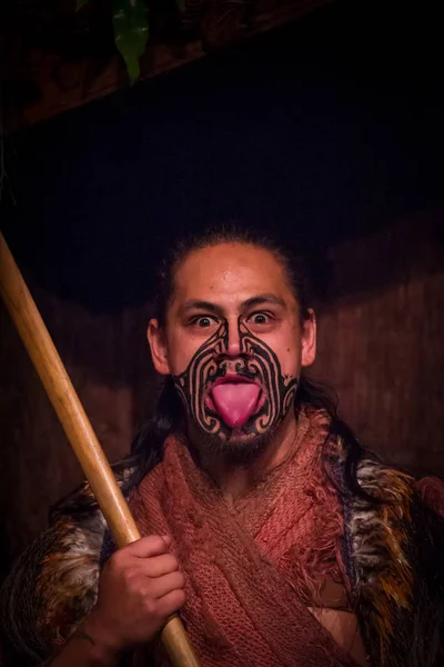 NORTH ISLAND, NEW ZEALAND- MAY 17, 2017: Maori man sticking out tongue with traditionally tatooed face and in traditional dress at Maori Culture, Tamaki Cultural Village, Rotorua, New Zealand — Stock Photo, Image