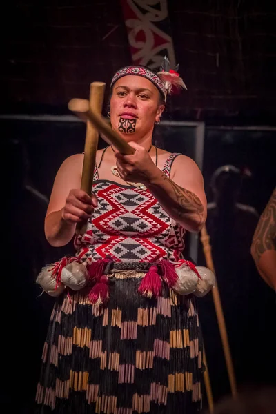 NORTH ISLAND, NEW ZEALAND - MAY 17, 2017: Close up of a Tamaki Maori woman with traditionally tatooed face and wearing traditional dress at Maori Culture village holding a wooden sticks in Tamaki — стоковое фото