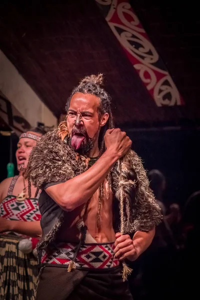 ISLA DEL NORTE, NUEVA ZELANDA - 17 DE MAYO DE 2017: Acercamiento de un hombre maorí con rostro tradicionalmente tatuado y vestido tradicional en la cultura maorí sosteniendo en sus manos una cuerda, Tamaki Cultural Village, Rotorua — Foto de Stock