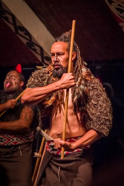 Noord eiland, Nieuw-Zeeland - 17 mei 2017: Takami Maori man met traditioneel tatooed gezicht in traditionele kleding bij Maori cultuur houden in zijn handen een houten stok, Tamaki Cultural Village, Rotorua — Stockfoto