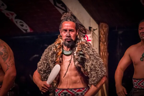 NORTH ISLAND, NEW ZEALAND - MAY 17, 2017: Serious Tamaki Maori man holding a wooden lance, with traditionally tatooed face wearing traditional dress at Maori Culture, Tamaki Cultural Village, in New — стоковое фото