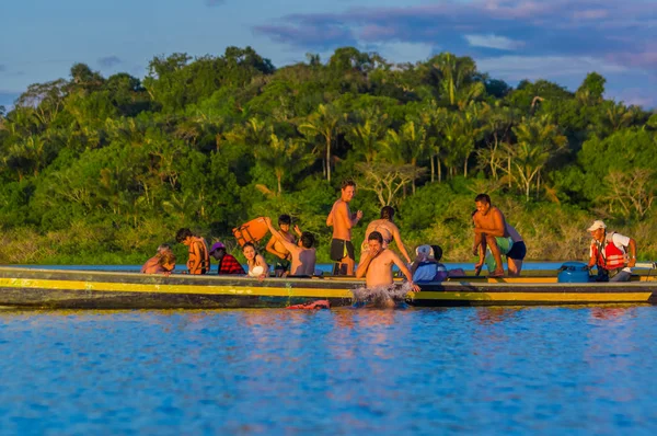 Cuyabeno, Ekvádor - 16 listopadu 2016: Mladí turisté skákání do laguny Grande proti západu slunce, Cuyabeno Wildlife Reserve, Jižní Amerika — Stock fotografie