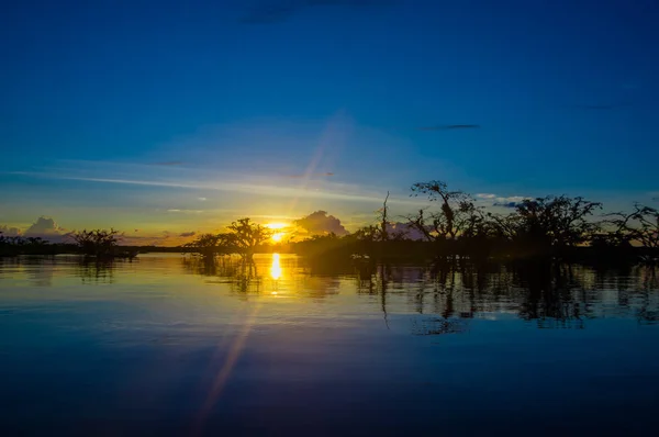 Linda silhueta contra um céu laranja ao pôr-do-sol sobre Laguna Grande no Parque Nacional Cuyabeno, no Equador — Fotografia de Stock