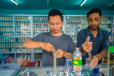 Bali, Endonezya - 08 Şubat 2017: şırınga ve esansları karıştırma Pipetler parfüm parfüm mağaza Denpasar Endonezya hazırlamak için kullanan kimliği belirsiz adam
