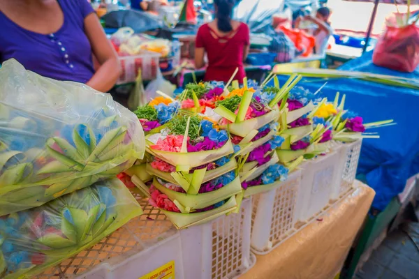 A market with a box made of leafs, inside an arrangement of flowers on a table, in the city of Denpasar in Indonesia — Stock Photo, Image