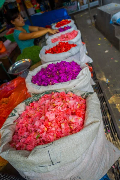 BALI, INDONESIA - MARCH 08, 2017: Unidentified people in outdoors Bali flower market, white sacks in row, flowers are used daily by Balinese Hindus as symbolic offerings at temples, inside of colorful — Stock Photo, Image