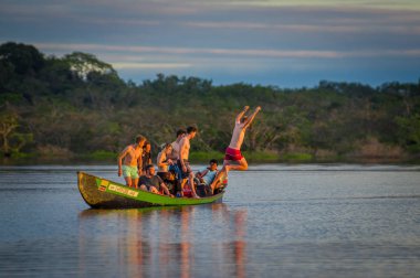 Cuyabeno, Ekvator - 16 Kasım 2016: Genç turist Lagoon Grande günbatımı, Cuyabeno Wildlife Reserve, Güney Amerika karşı içine atlama