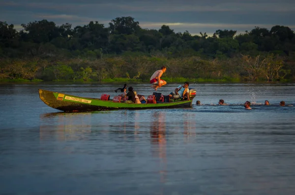 CUYABENO, ECUADOR - 16 DE NOVIEMBRE DE 2016: Jóvenes turistas saltan a la laguna Grande contra el atardecer, Reserva de Vida Silvestre Cuyabeno, América del Sur — Foto de Stock