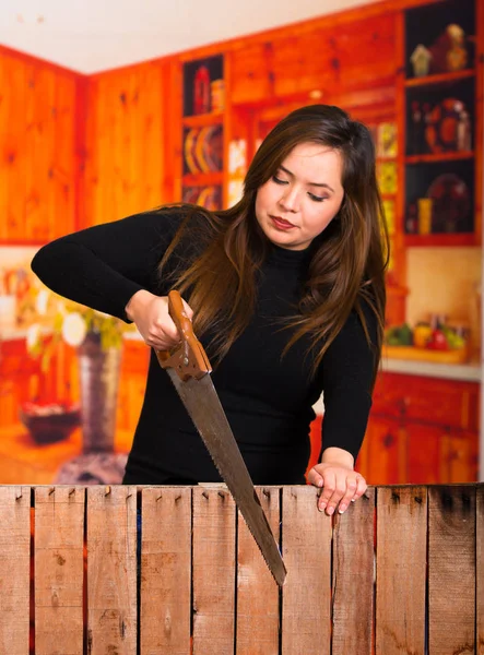 Mooie jonge vrouw snijden hout met een zaag — Stockfoto