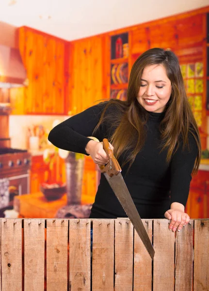 Mooie jonge vrouw snijden hout met een zaag — Stockfoto