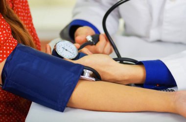 Bir kadın ile bir tensiometer onu kolundan Oda arka plan danışmanlık doktor sırasında darbe duymak steteskop kullanarak genç bir doktorun yakın çekim