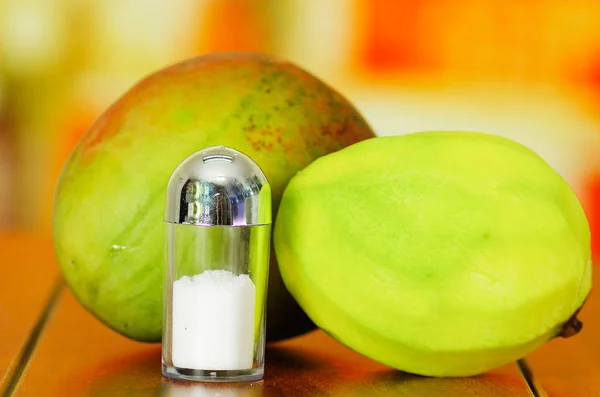 Raw and peeled mango behind salt shaker — Stock Photo, Image