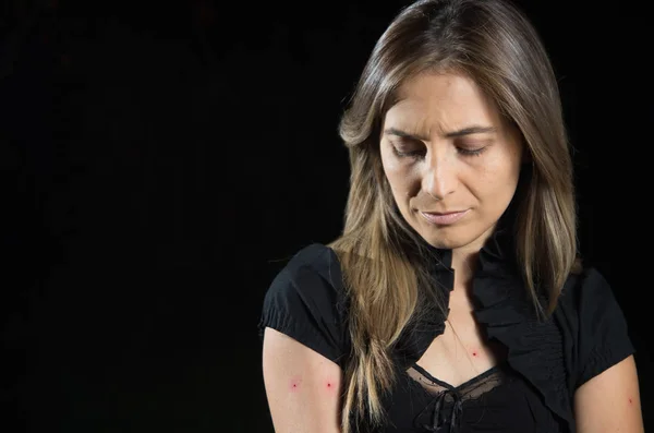 Mujer joven con puntos rojos en los brazos después de una picadura de mosquito, en un fondo negro — Foto de Stock