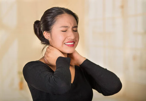 Young hispanic woman posing for camera showing signs of neck pain, holding hands on painful part of body, injury concept — Stock Photo, Image