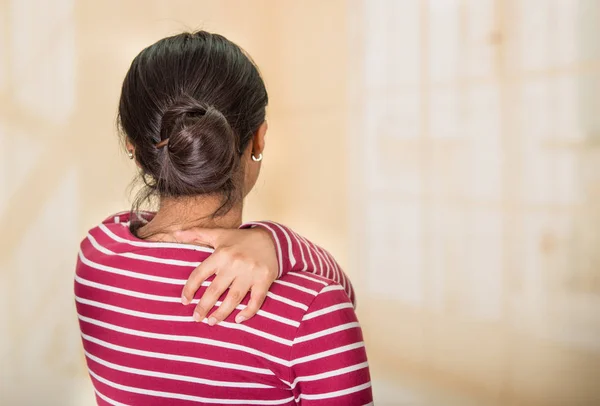 Jonge Spaanse vrouw poseren voor de camera tekenen van pijn in de schouder, hand in hand op de pijnlijke lichaamsdeel, letsel concept — Stockfoto