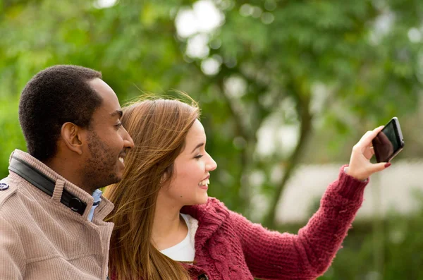 Hermosa y sonriente feliz pareja joven interracial en parl tomando una selfie — Foto de Stock