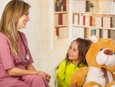 Güzel doktor office arka planda boynunda steteskop giyen bir çocuk bir hastanede konuşurken