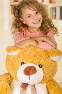 Gülümseyen ve oyuncak ayı s kafasının içinde bir doktor office arka plan üzerinde poz genç güzel bir kız portresi