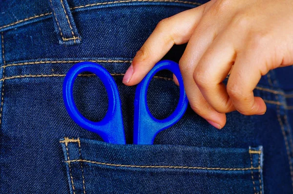 Forbici blu all'interno di jeans tasca posteriore con una mano — Foto Stock