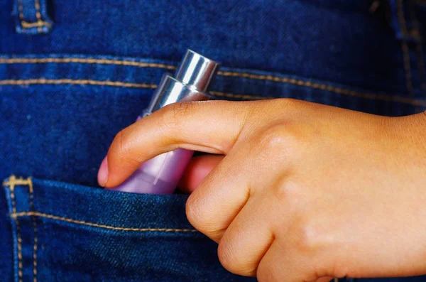 Kvinna hand hållande en rosa spray insidan jeans bakficka — Stockfoto