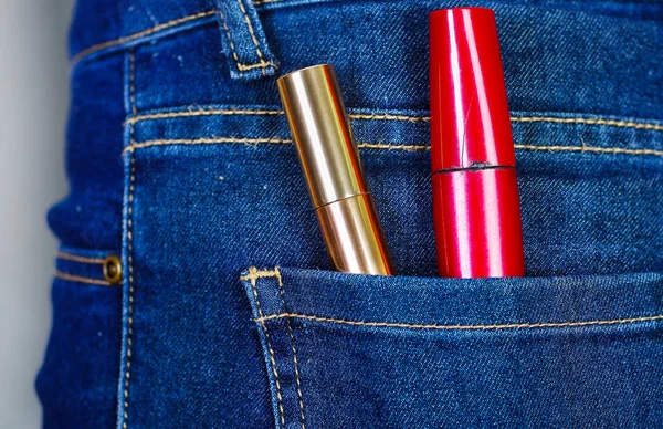 Красные и золотые помады в заднем кармане джинсов — стоковое фото