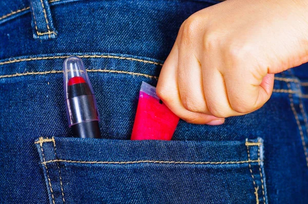 Mano de mujer sosteniendo un lápiz labial dentro del bolsillo trasero de los vaqueros — Foto de Stock