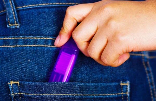 Mulher segurando uma caixa roxa com uma escova de dentes dentro do bolso traseiro de jeans — Fotografia de Stock