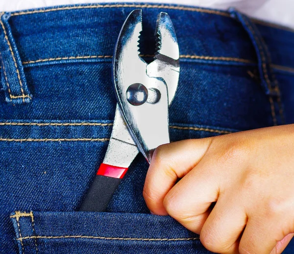 Woman hand holding a plier inside of jeans back pocket — Stock Photo, Image