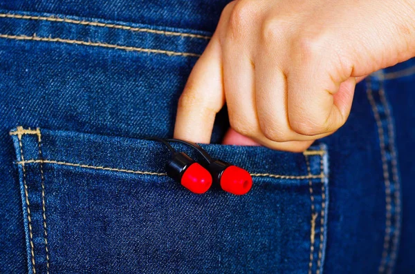 Hand van de vrouw met een zwart met rode hoofdtelefoon binnenkant jeans zak terug — Stockfoto