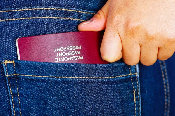 Mano de mujer sosteniendo un pasaporte dentro del bolsillo trasero de jeans —  Fotos de Stock